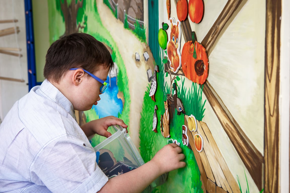 A Male Teenager with Disabilities Playing with Pictured Magnets